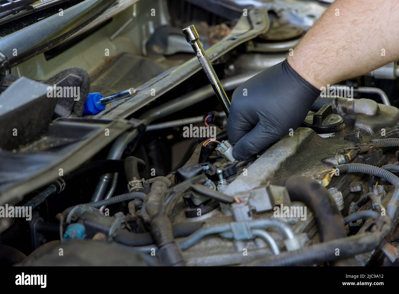 Il meccanico esegue la diagnostica e la sostituzione di una candela dell'auto Foto Stock