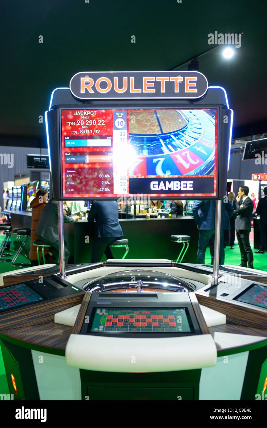 Tavolo americano della roulette che lavora ad un casinò, i giocatori offuscati che si levano in piedi intorno ai tavoli su uno sfondo. Mostra del settore del gaming. Novembre 24, 2021. KY Foto Stock Tavolo americano della roulette che lavora ad un casinò, i giocatori offuscati che si levano in piedi intorno ai tavoli su uno sfondo. Mostra del settore del gaming. Novembre 24, 2021. KY Foto Stock