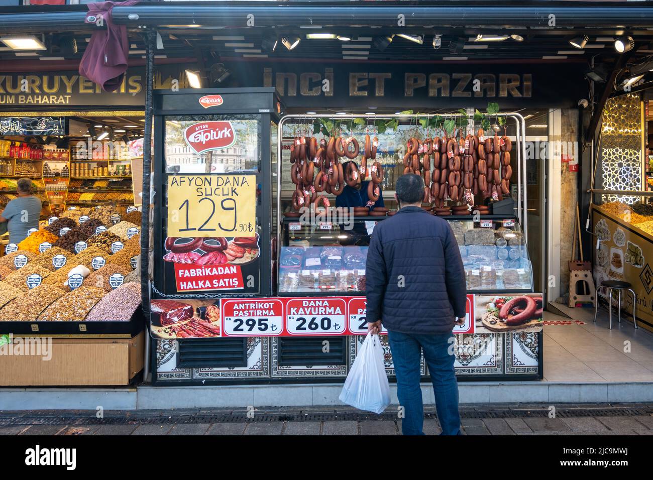 Un uomo in piedi di fronte ad un negozio di salsiccia per strada. Istanbul, Türkiye. Foto Stock