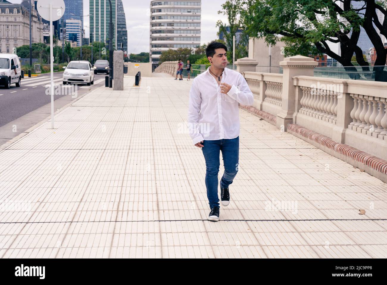 Giovane uomo latino elegante che cammina lungo la strada. Foto Stock