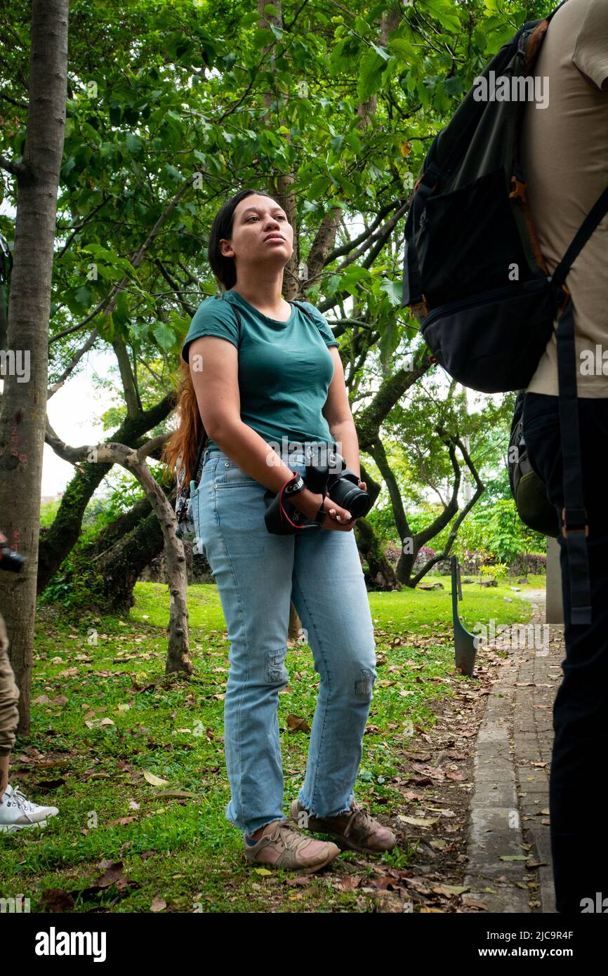 Medellin, Antioquia, Colombia - Febbraio 19 2022: Donna colombiana con capelli lunghi e marroni tiene la sua macchina fotografica ad una Convenzione fotografica Foto Stock