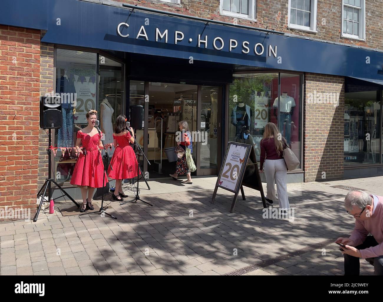 Newbury, Berkshire, Inghilterra, Regno Unito. 2022. Cantanti in abiti rossi seranade passa vicino sulla High Street a Newbury in un pomeriggio di sole. Inghilterra Regno Unito. Foto Stock