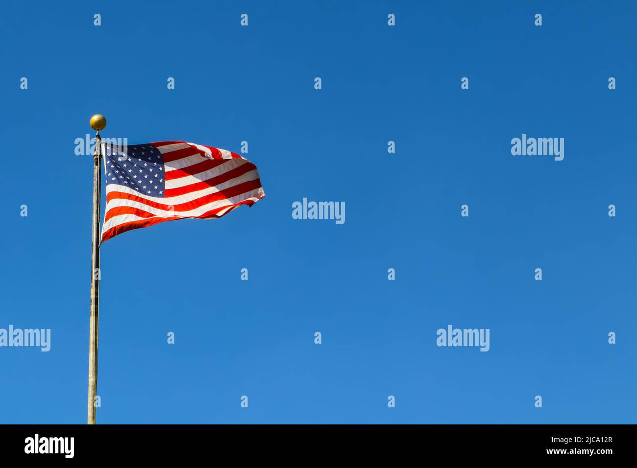 Bandiera americana che sventola contro il cielo molto blu sul flagpole - spazio per la copia Foto Stock