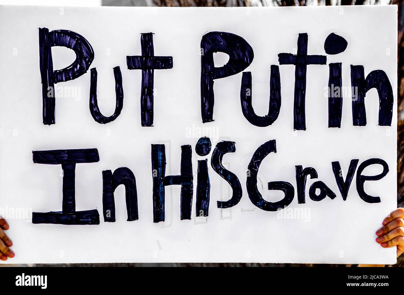 Il segno scritto a mano al rally pro-ucraino legge mettere Putin nella sua tomba Foto Stock