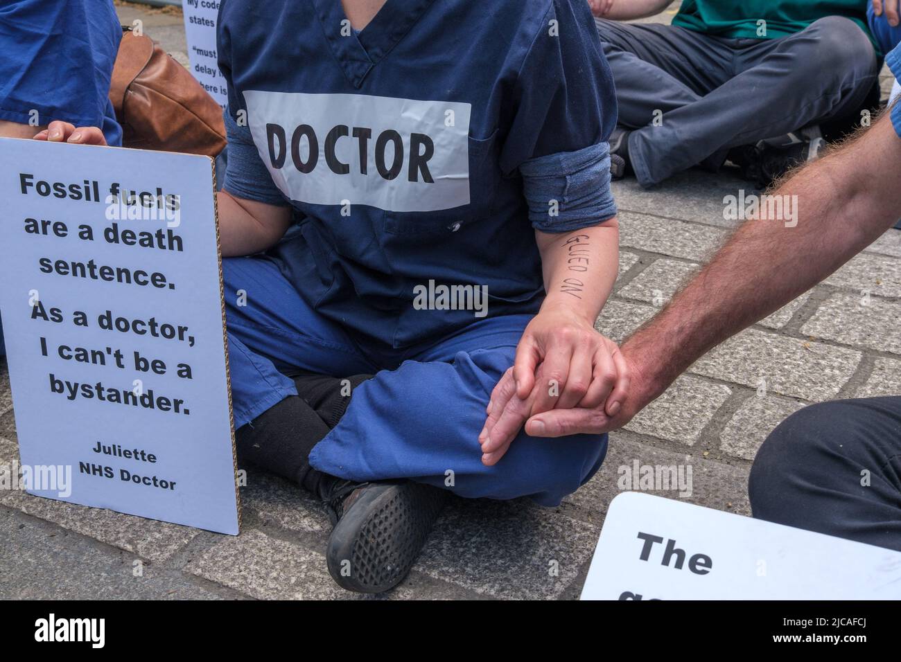 Londra, Regno Unito. 11 giugno 2022. Medici, ostetriche, infermieri e altro personale medico in Medici per la ribellione estinzione bloccare l'ingresso a Downing St in una protesta sit-down contro il governo che approva il nuovo combustibile fossile per il Regno Unito. Le mani incollate e sedettero di fronte all'entrata, dicendo che il governo ci sta tradendo non agendo di fronte alla crisi climatica e che il combustibile fossile sta uccidendo madri e bambini. Peter Marshall / Alamy Live News Foto Stock