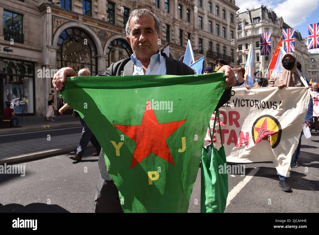 Londra, Inghilterra, Regno Unito. 11th giugno 2022. Il manifestante detiene la bandiera YPJ (YPJ fa parte delle forze democratiche siriane, ed è composto principalmente dai curdi), durante la demonestazione. I curdi e i loro sostenitori marciarono dalla sede centrale della BBC London a Downing Street, per opporsi alla nuova offensiva della Turchia contro i ribelli curdi in Iraq e Siria. (Credit Image: © Thomas Krych/ZUMA Press Wire) Foto Stock