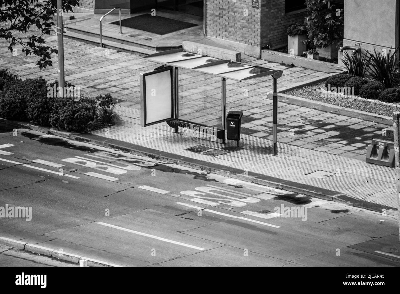 Colpo ad angolo alto di una fermata dell'autobus vuota su un marciapiede contro una strada asfaltata Foto Stock