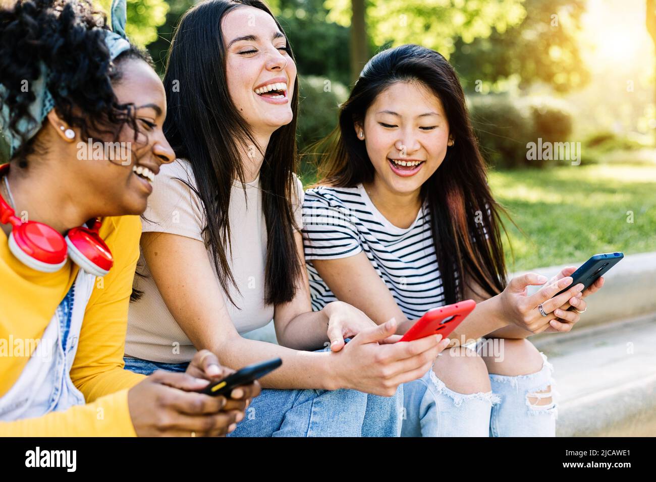 Giovane donna multirazziale amici divertirsi utilizzando i telefoni cellulari in strada Foto Stock