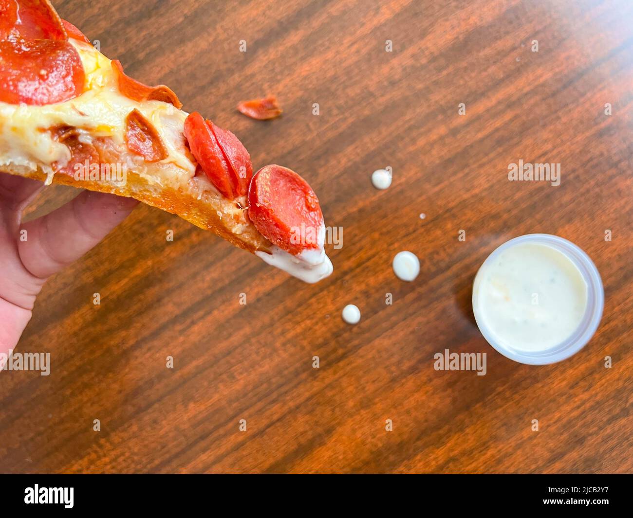 Una fetta di pizza immersa nel rancore da una mano di un uomo con chiodi a dita dipinti Foto Stock