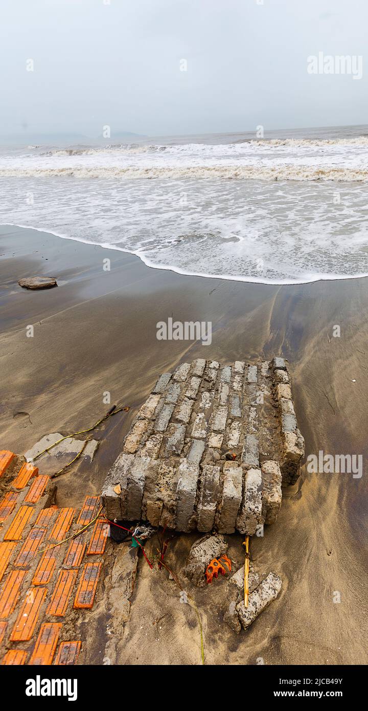 Il cambiamento climatico ha creato l'erosione della spiaggia e parte del muro di mare è caduto nella spiaggia diretta per l'oceano. Foto Stock