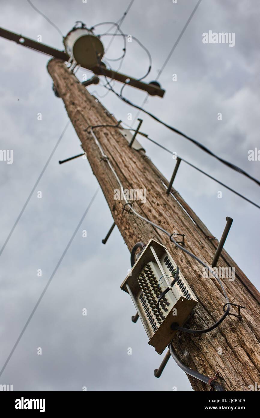 Palo del telefono che guarda in alto il dettaglio in giorno nuvoloso per la comunicazione e l'alimentazione Foto Stock