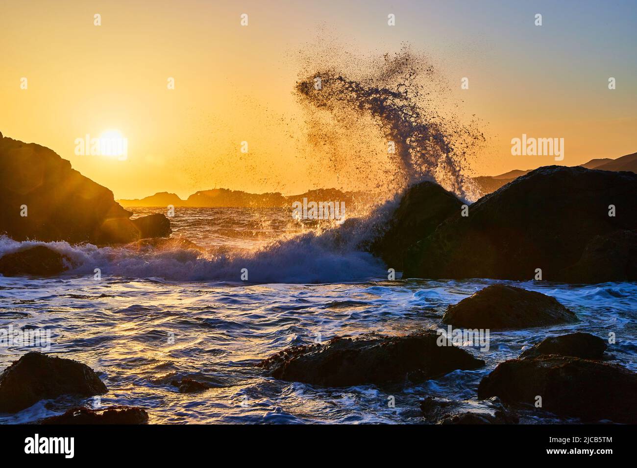 Incredibile spruzzi di onde oceaniche al tramonto dalle grandi rocce Foto Stock