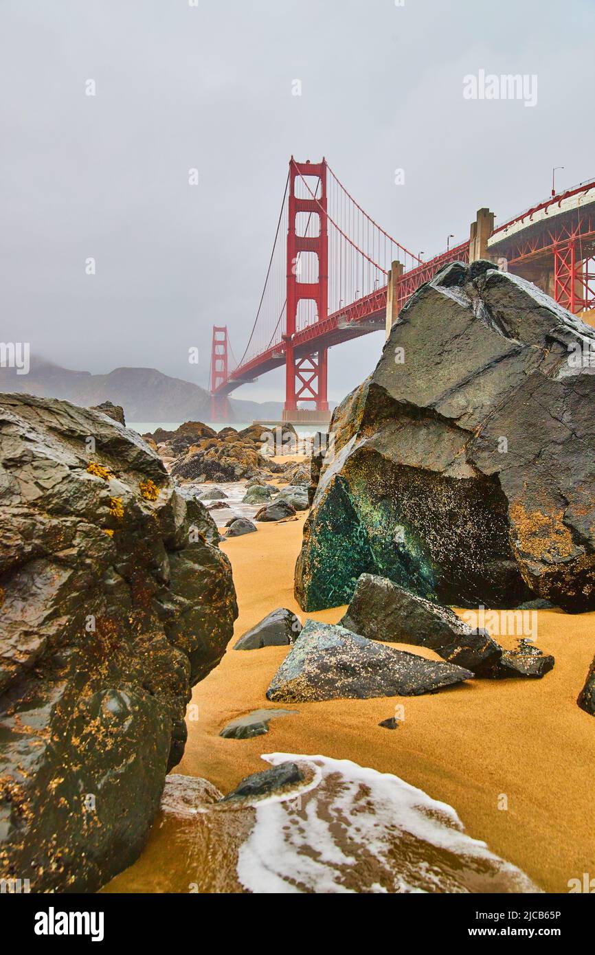 Rocce che coprono la spiaggia sabbiosa in mattinata di nebbia presso il Golden Gate Bridge a San Francisco Foto Stock