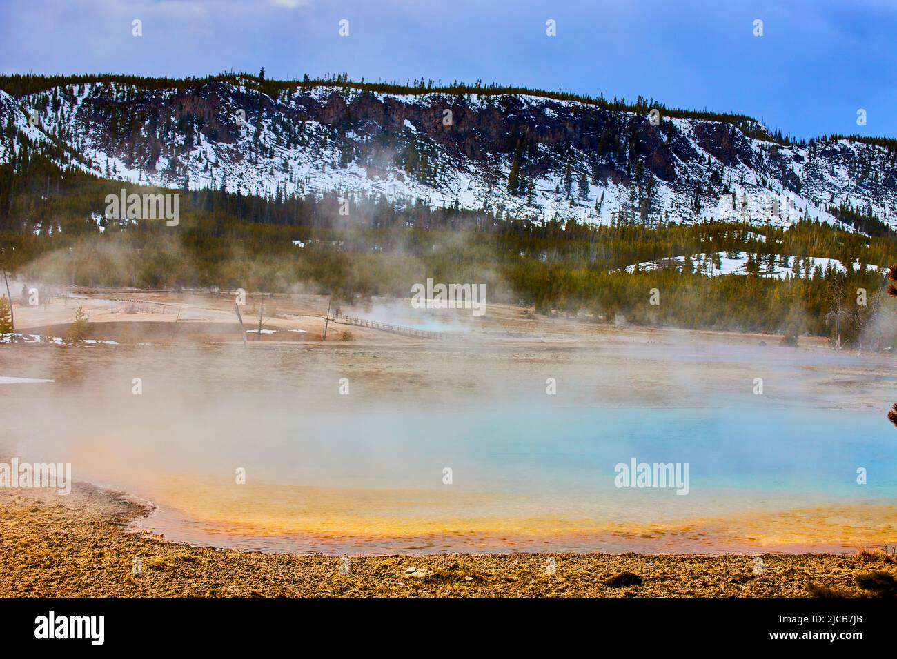 Il vapore solforico passa sopra la splendida sorgente delle montagne innevate di Yellowstone Foto Stock