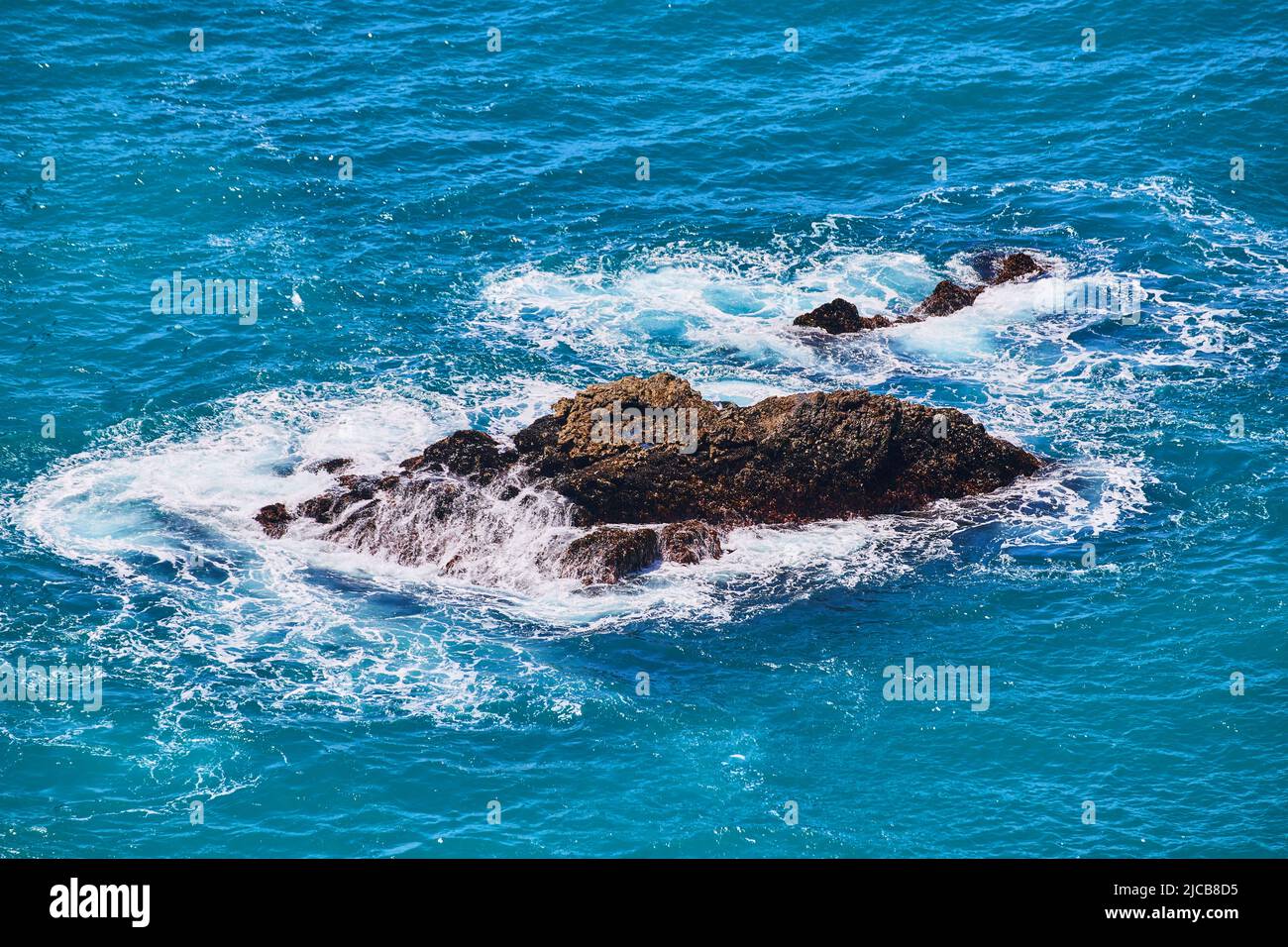 Grandi rocce nell'acqua dell'oceano con onde che si infrangono in loro Foto Stock