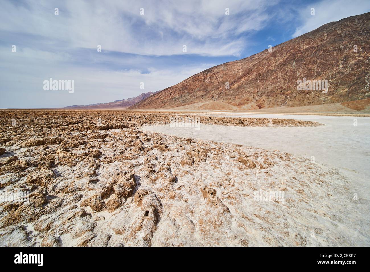 Formazioni saline del bacino di Badwater in dettaglio accanto al sentiero e alle montagne Foto Stock