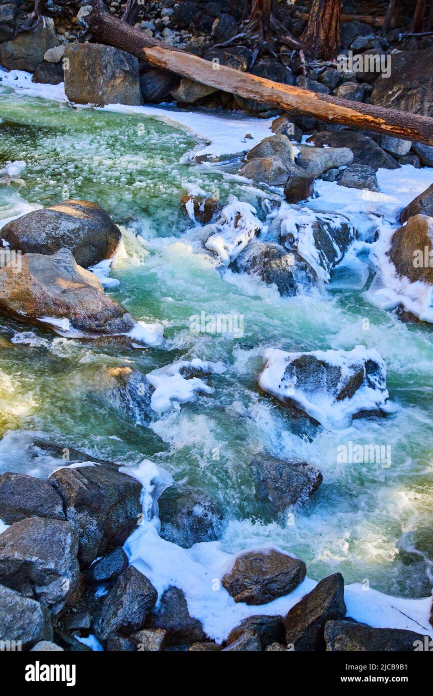 Fiume di sorgente a Yosemite pieno di neve e rocce ghiacciate Foto Stock