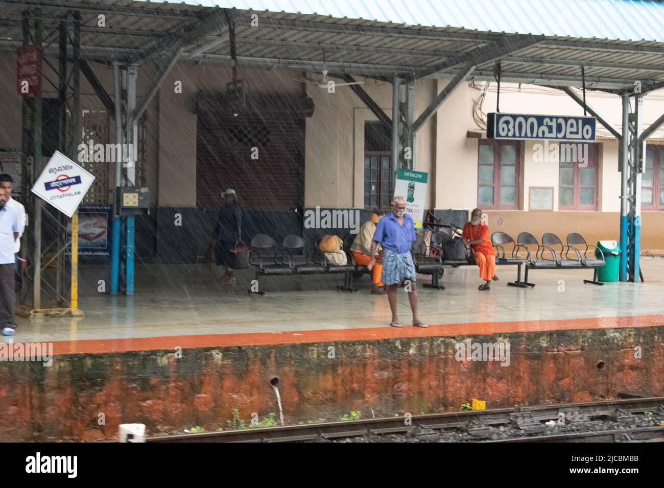 Stazione ferroviaria indiana durante la pioggia, la gente sta aspettando. Foto Stock