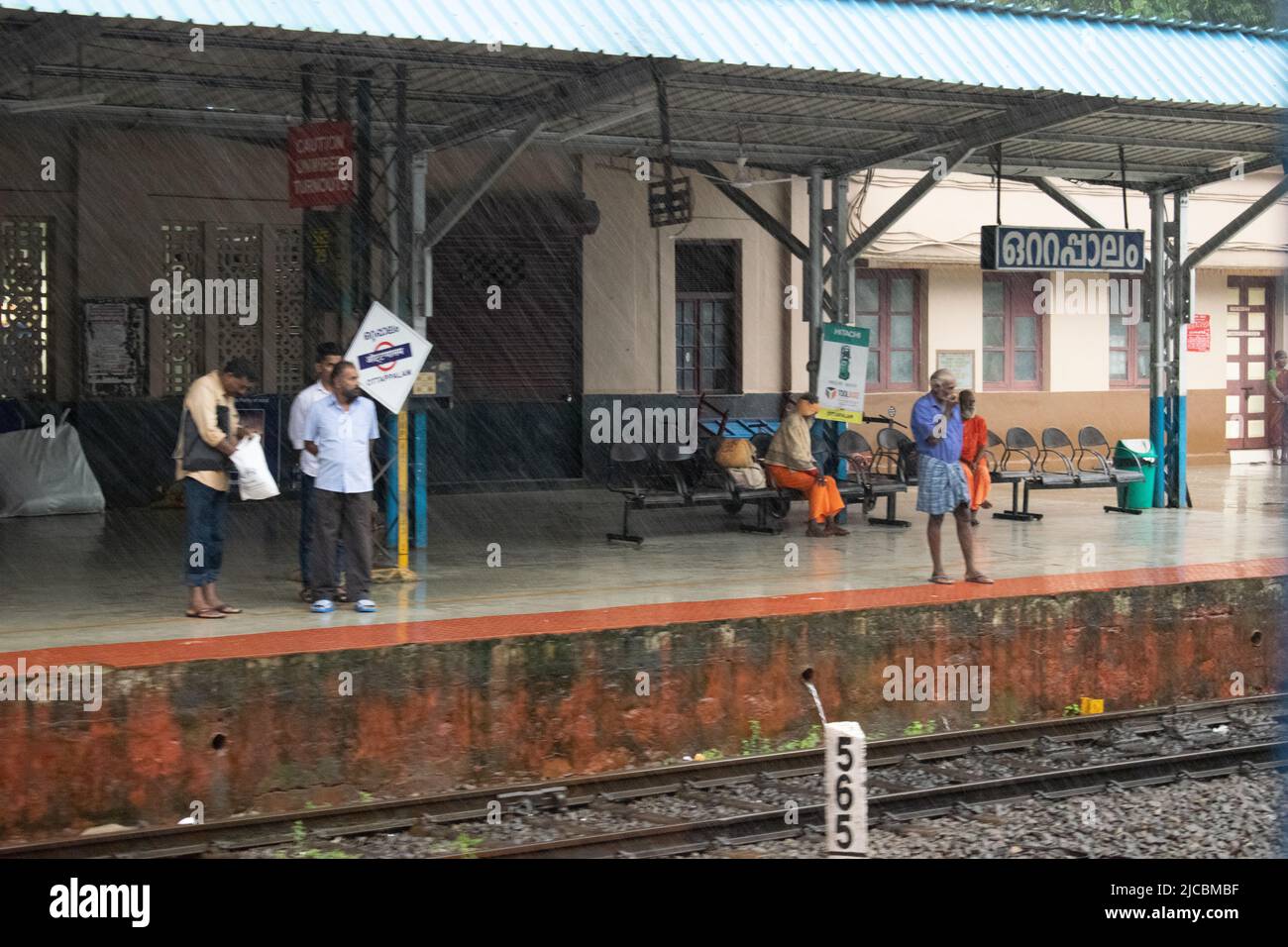 Stazione ferroviaria indiana durante la pioggia, la gente sta aspettando. Foto Stock