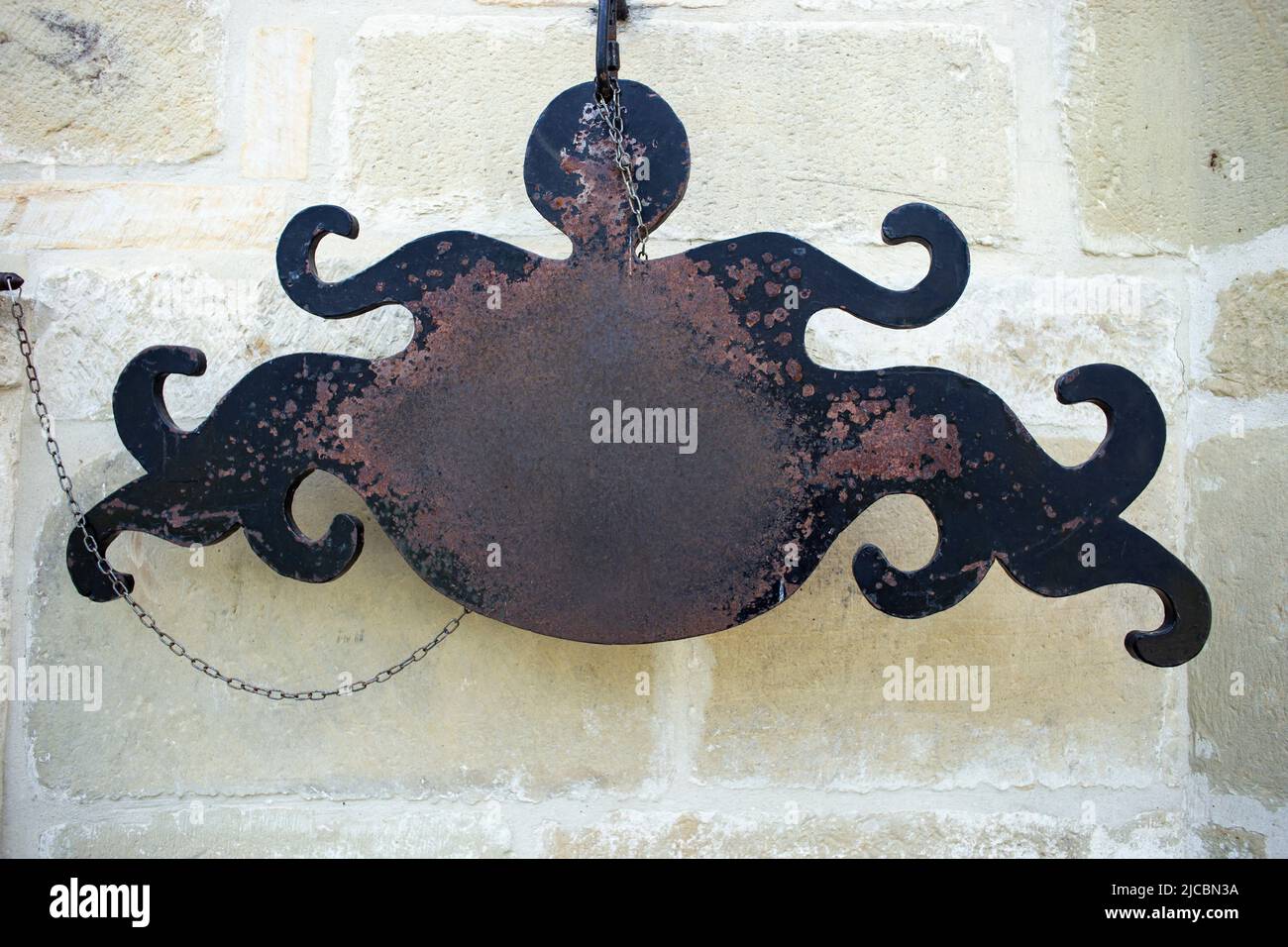 segno di ferro a forma di polpo , spazio di copia arrugginito per il testo sullo sfondo della parete di pietra Foto Stock