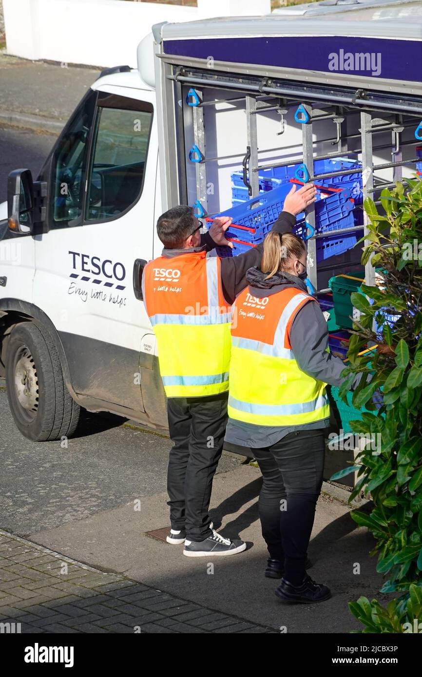 Insoliti due addetti al supermercato Tesco che lavorano insieme hanno assunto la formazione del conducente di consegna cernita alimentari alimentari online shopping ordine Essex Inghilterra UK Foto Stock