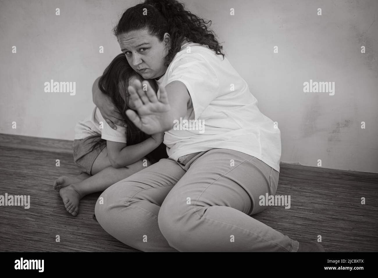 Ritratto in bianco e nero di famiglia abusata. Giovane madre paura donna tenere figlia ragazza, stretching mano per fermare. Foto Stock