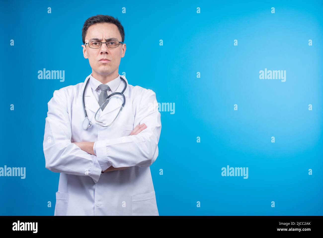 Medico rigoroso in occhiali contro sfondo blu Foto Stock