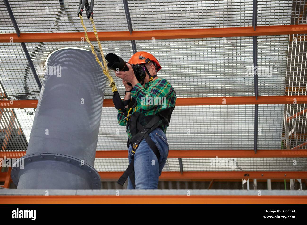 Fotografo che lavora in altezza con imbracatura di sicurezza e casco Foto Stock