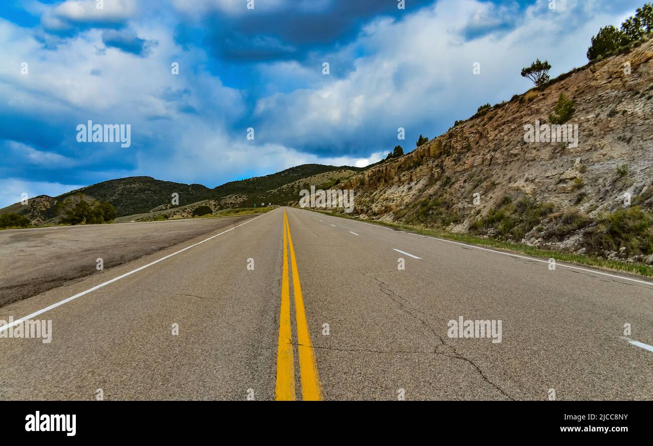 Strada asfaltata dritta e piana che si estende fino alla distanza oltre l'orizzonte in Utah, USA Foto Stock