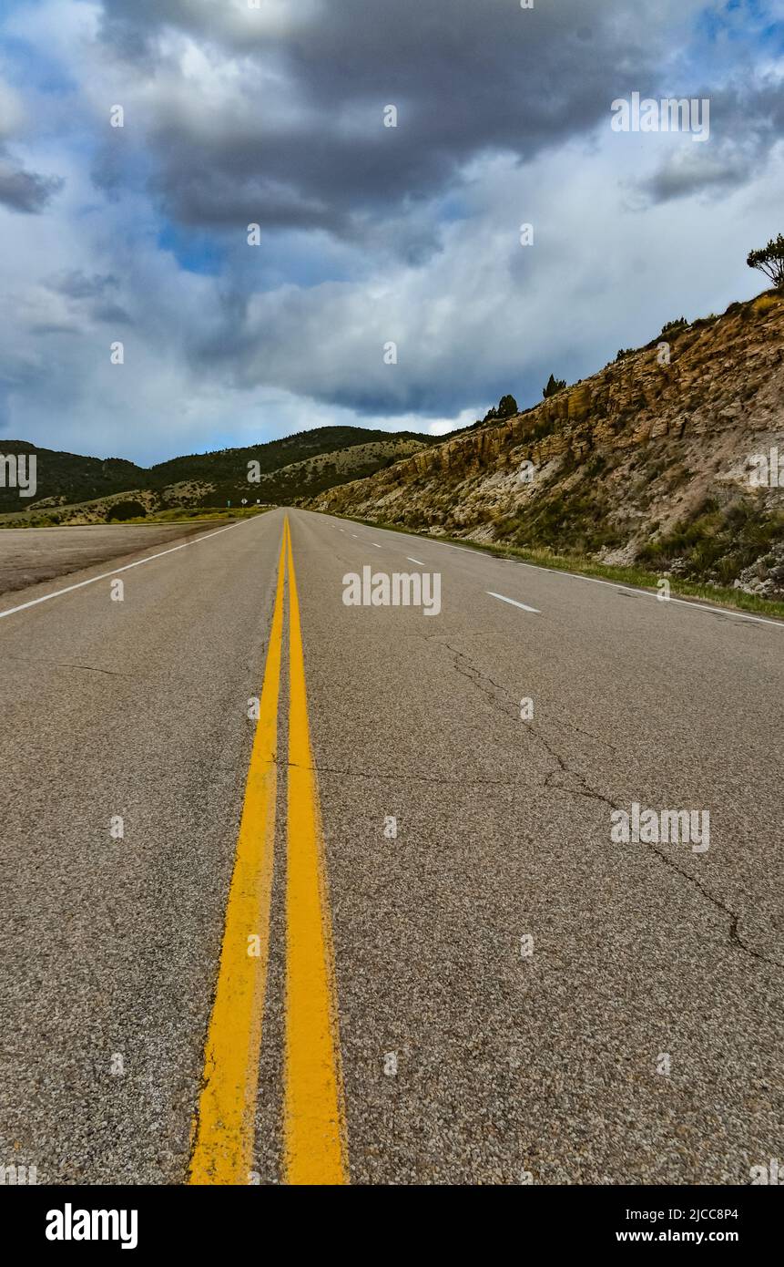 Strada asfaltata dritta e piana che si estende fino alla distanza oltre l'orizzonte in Utah, USA Foto Stock