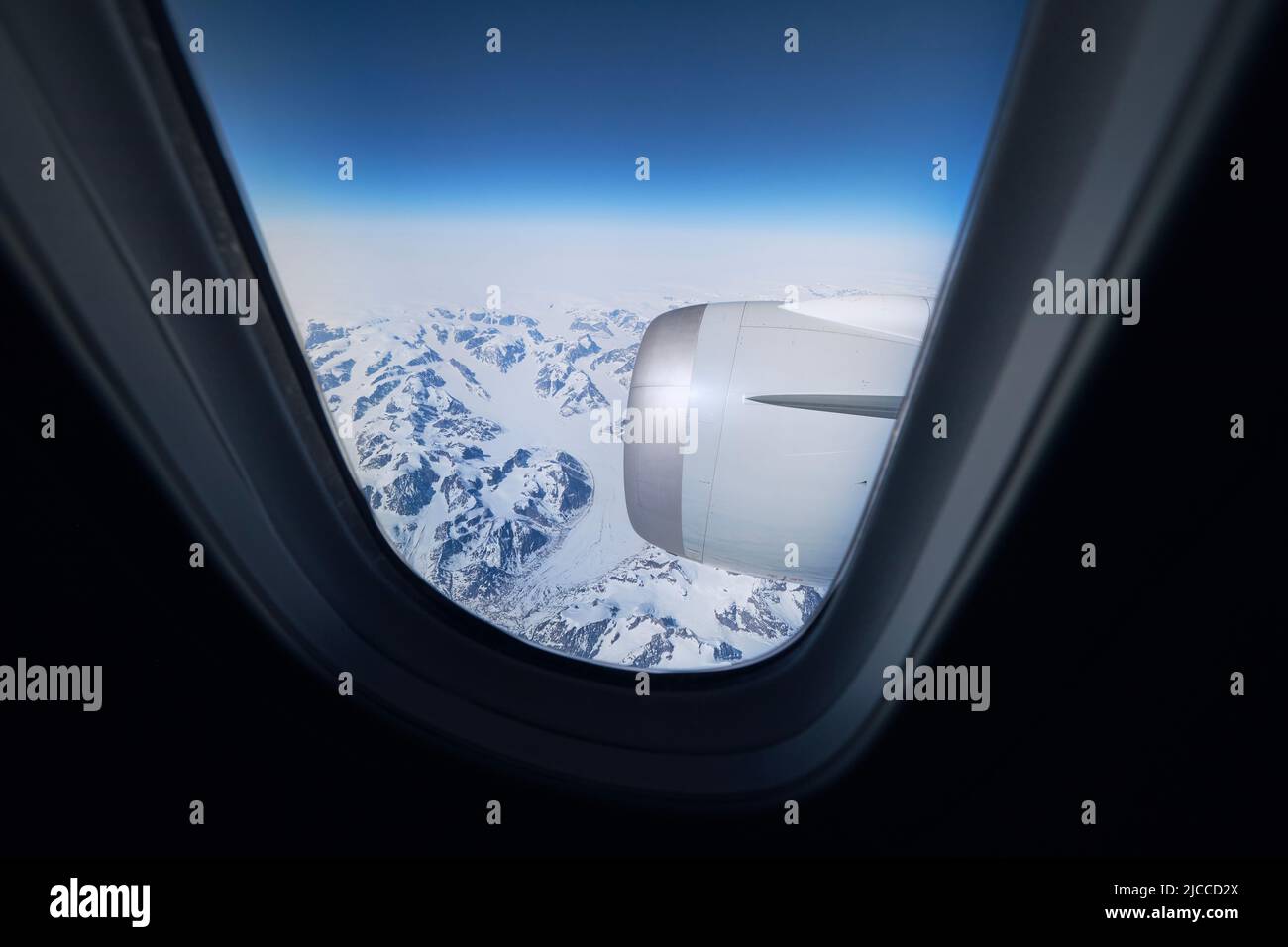 Vista dalla finestra dell'aeroplano durante il volo sopra le montagne innevate della Groenlandia. Foto Stock