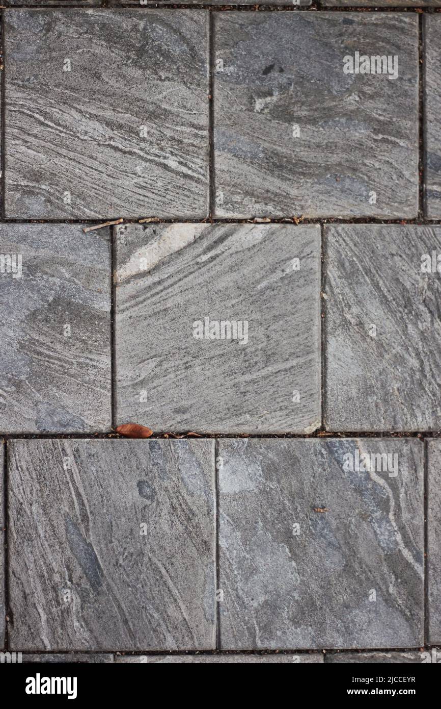 Piastrelle di marmo quadrate tipiche e comuni che servono come pavimentazione su un elegante marciapiede. Foto Stock