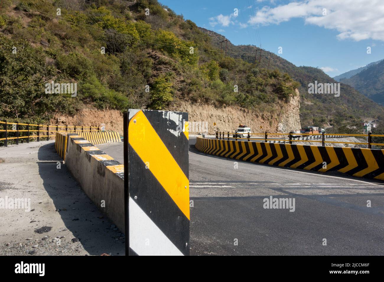 Un ampio angolo di una strada asfaltata per tutte le stagioni con barriere in calcestruzzo gialle. Uttarakhand, India. Foto Stock