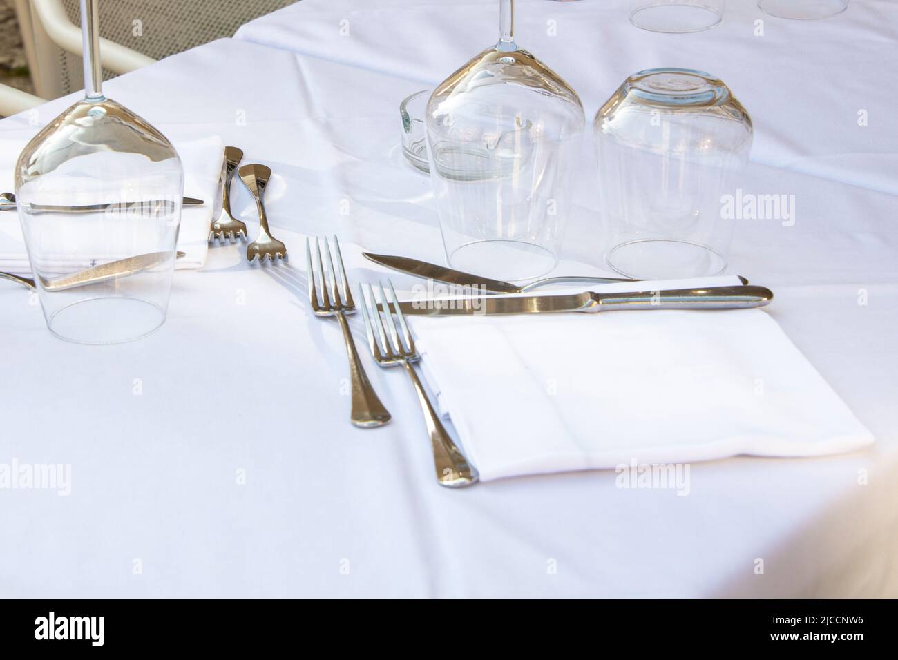 Tavolo da lavoro per due in colore bianco con forchette, coltelli, tovaglioli e tovaglie Foto Stock