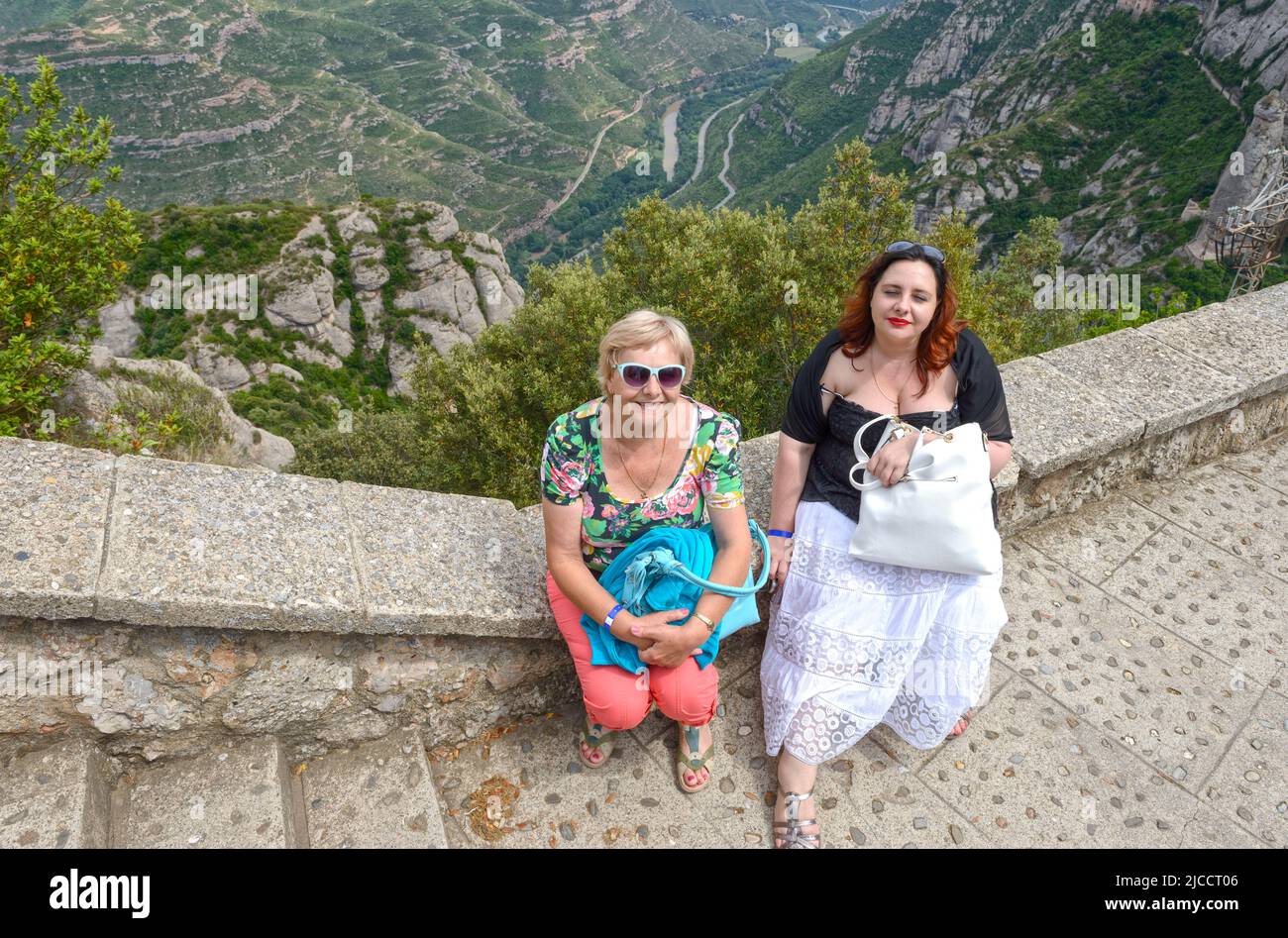 Ritratto di madre e figlia che sono seduti sul parapetto in Abbazia di Montserrat sulla valle del fiume Llobregat sfondo, Barcellona. Foto Stock