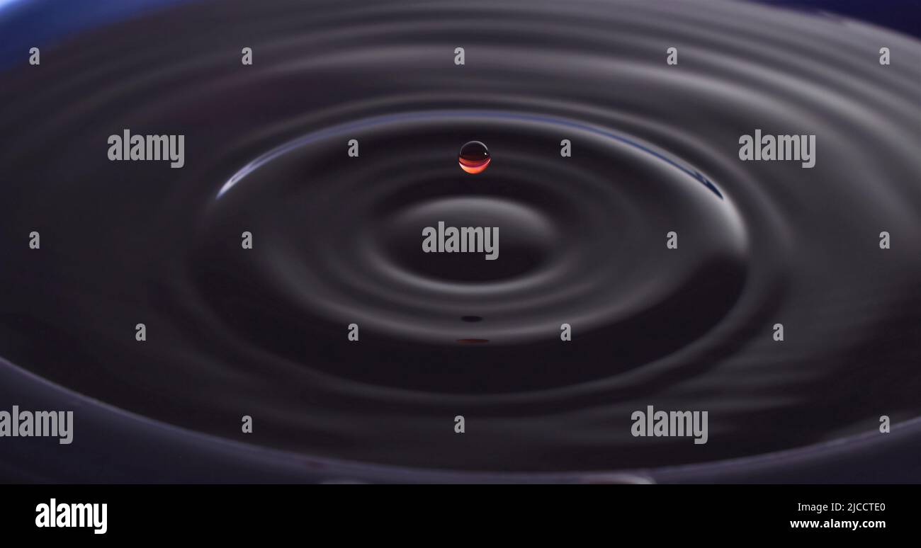 Water drop Fotografia, primo piano di gocce d'acqua rossa in acqua di colore blu scuro. Foto Stock