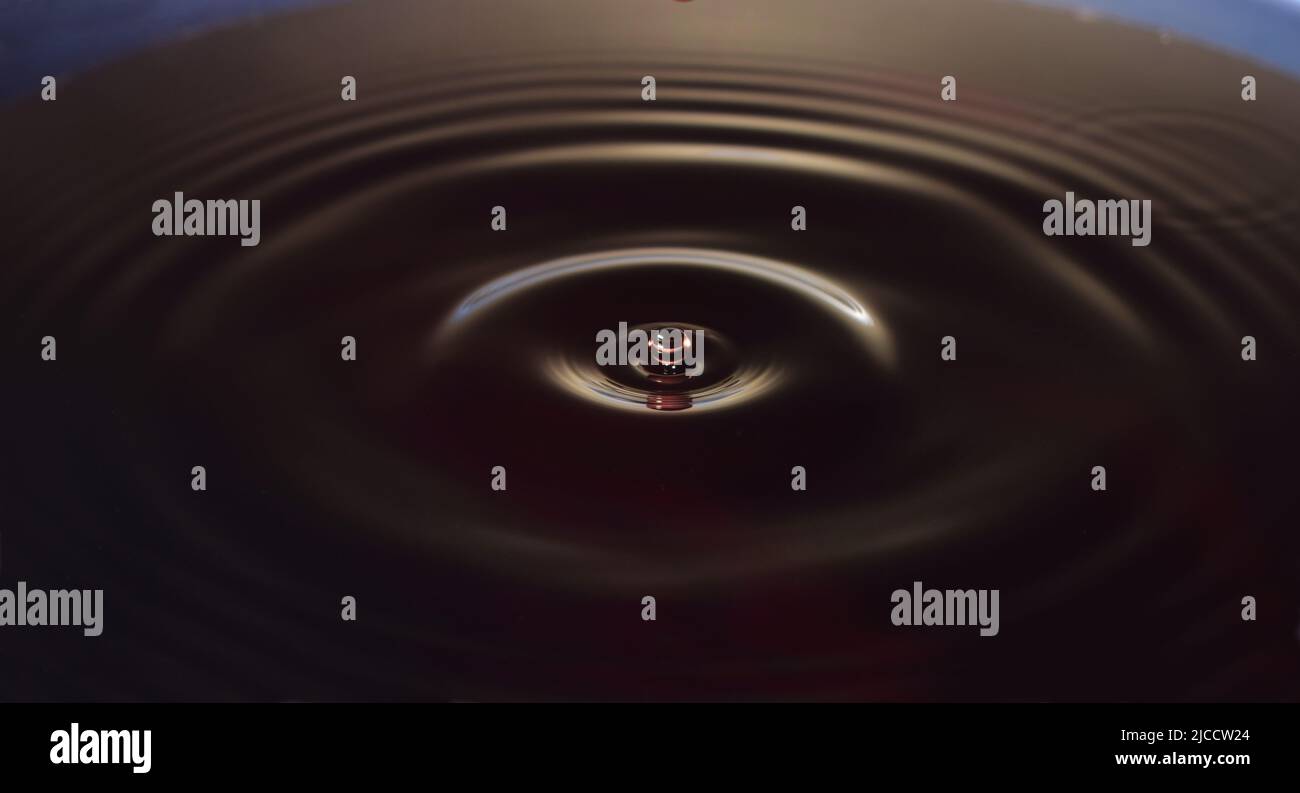 Water drop Fotografia, primo piano di gocce d'acqua rossa in acqua di colore blu scuro. Foto Stock