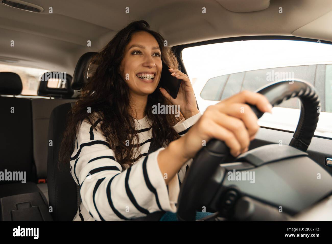 Conducente donna che guida auto parlare al telefono seduto in Automobile Foto Stock