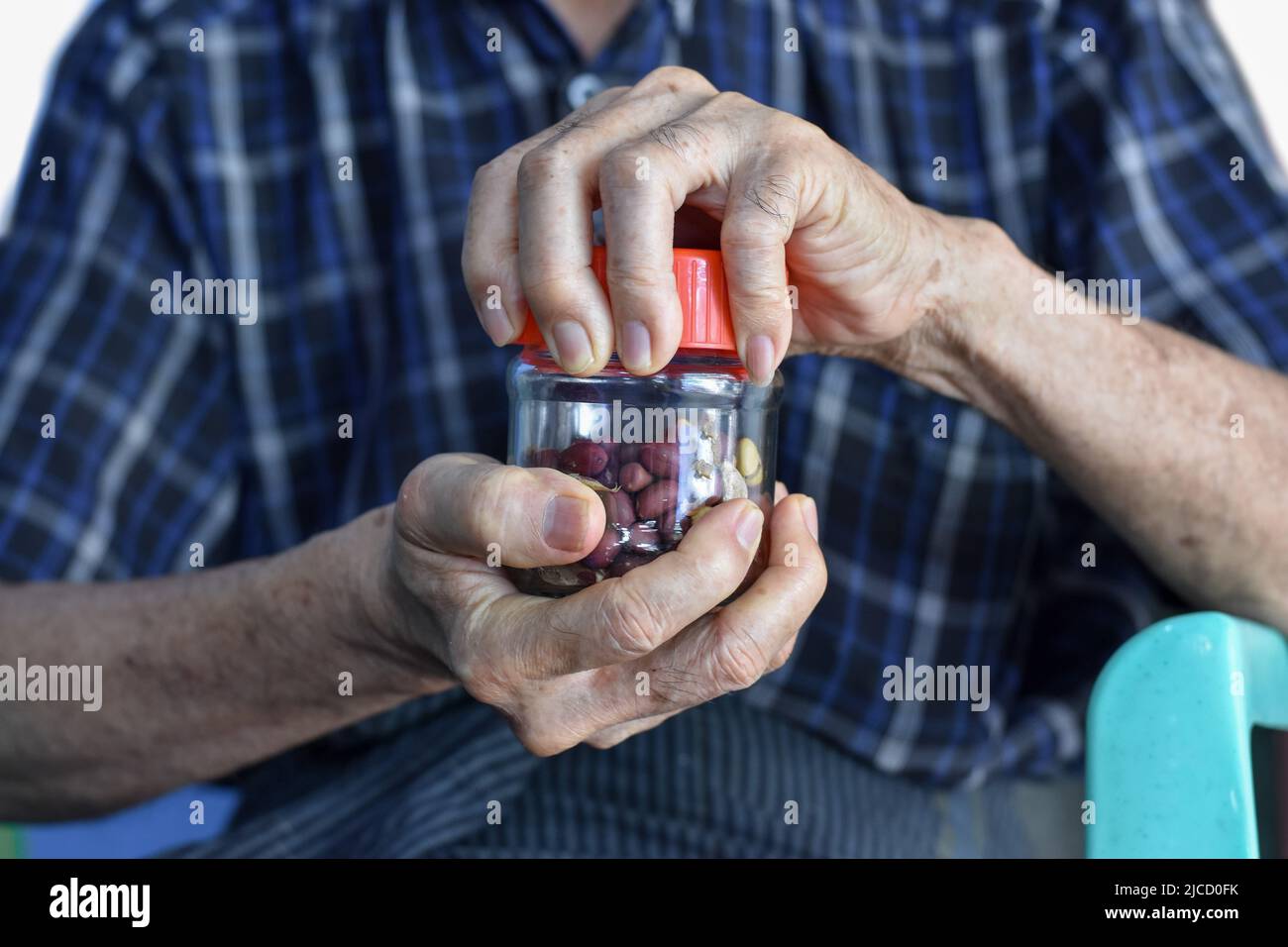 Uomo cinese asiatico avvitando il tappo di bottiglia di vetro. Concetto di forza e potenza muscolare della mano. Foto Stock