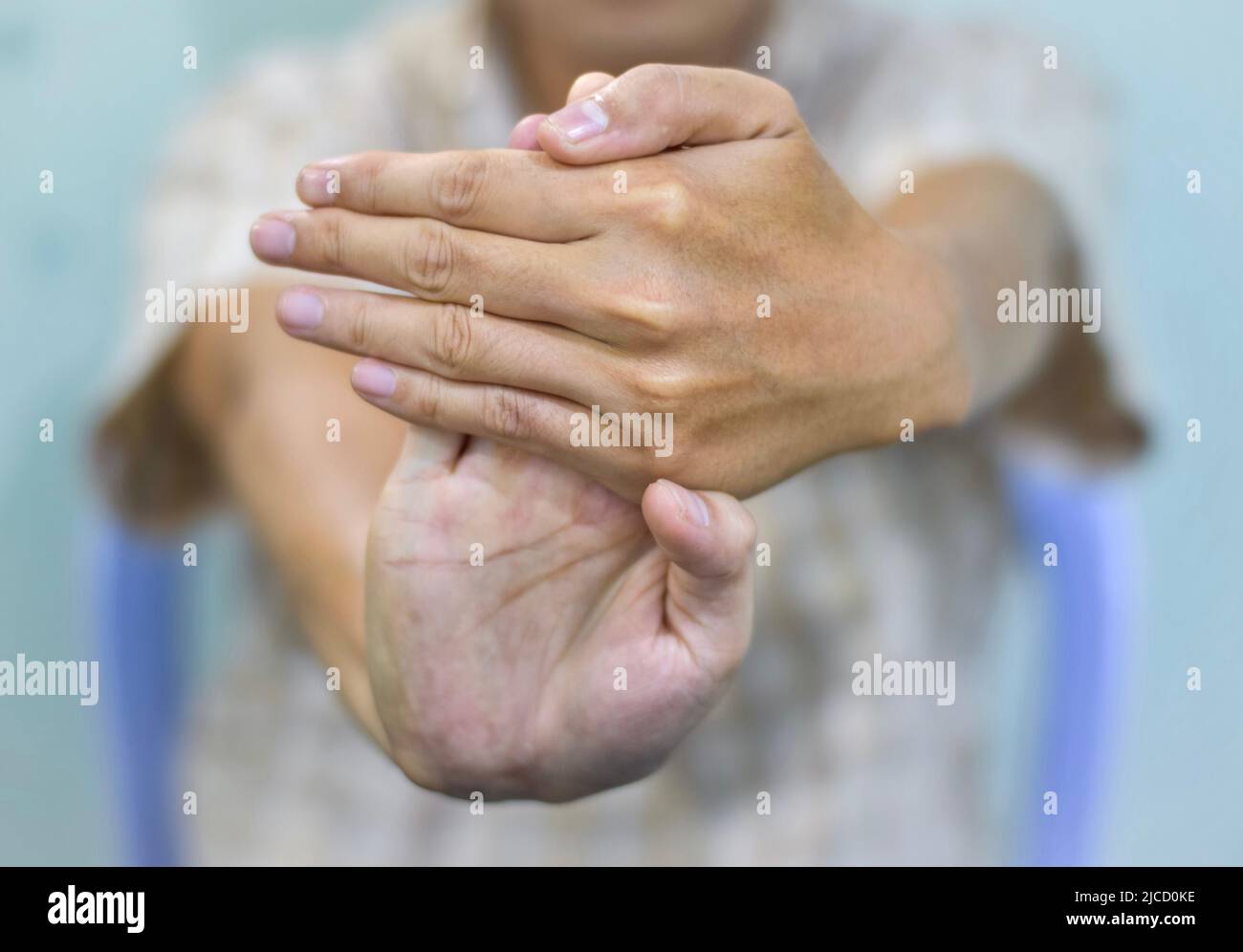 Rafforzamento dell'esercizio per i muscoli del braccio di giovane paziente asiatico con spasmo muscolare. Foto Stock