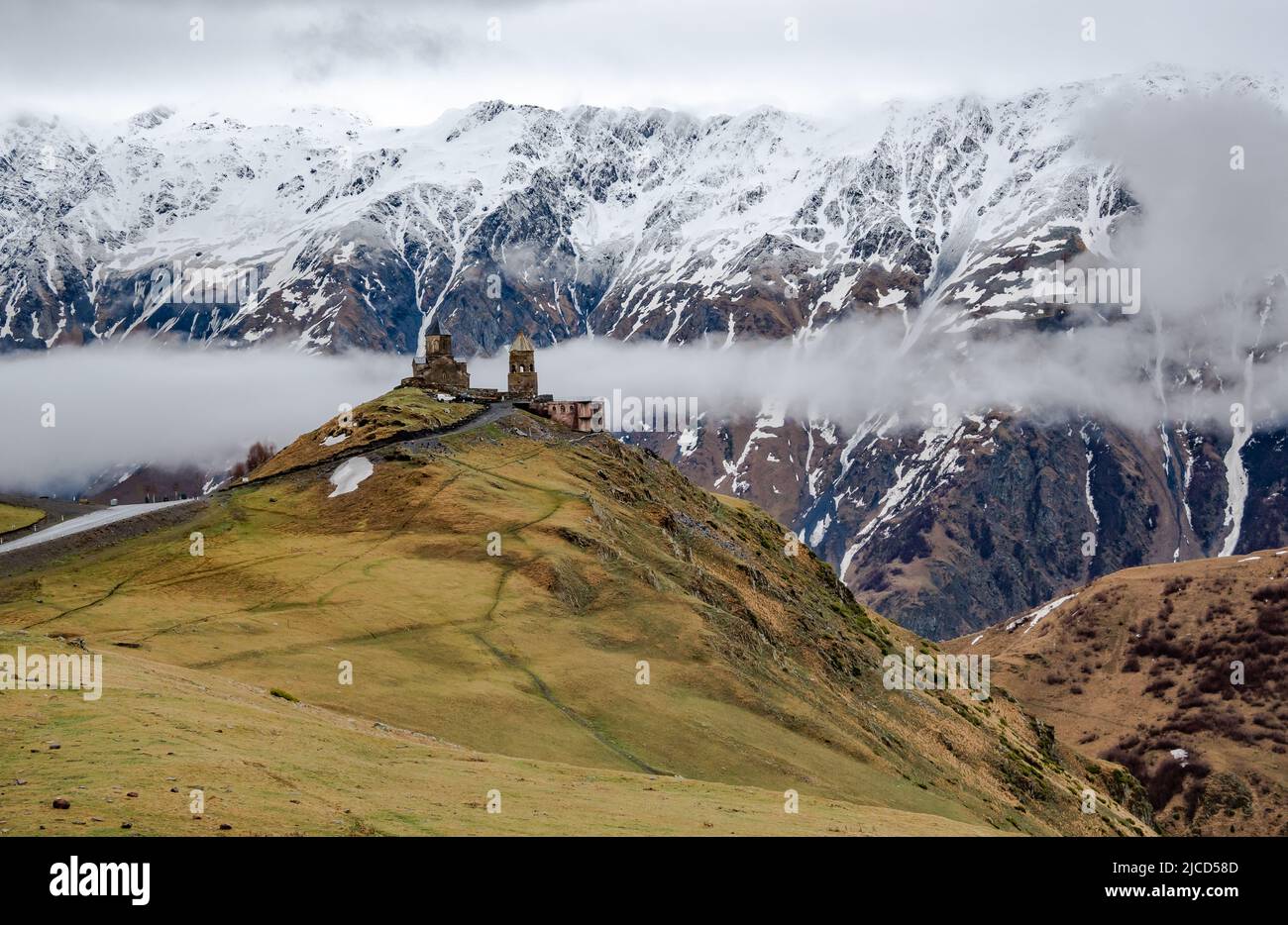 La Chiesa della Trinità di Gergeti sorge di fronte ai monti del Caucaso maggiore. Stepantsminda, Repubblica di Georgia. Foto Stock