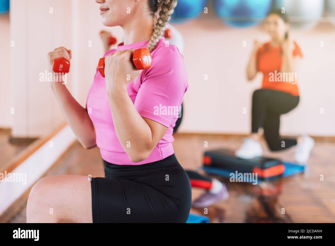 Gruppo di donne che fanno affondi con manubri nelle loro mani Foto Stock