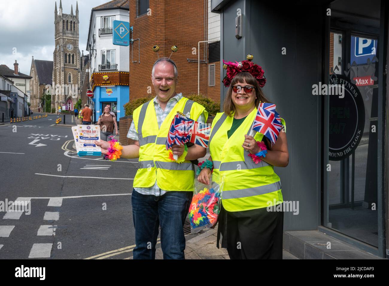 Volontari che consegnano i programmi del Victoria Day e le bandiere di Union Jack all'evento annuale ad Aldershot, Hampshire, Inghilterra, Regno Unito, giugno 2022 Foto Stock