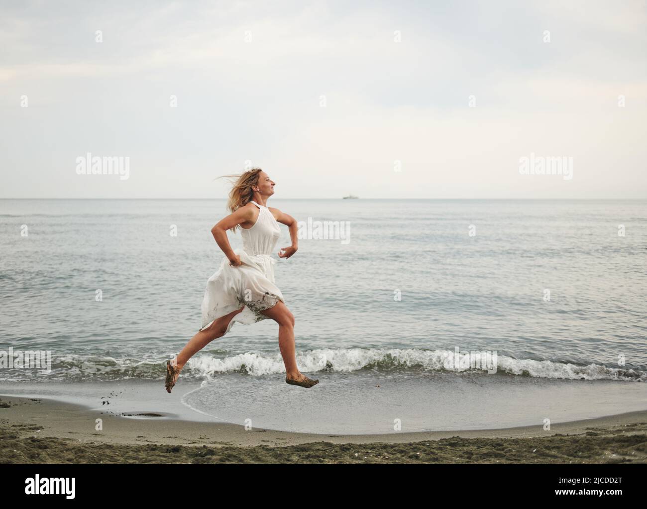 salta sulle ragazze della riva dell'oceano in bianco Foto Stock