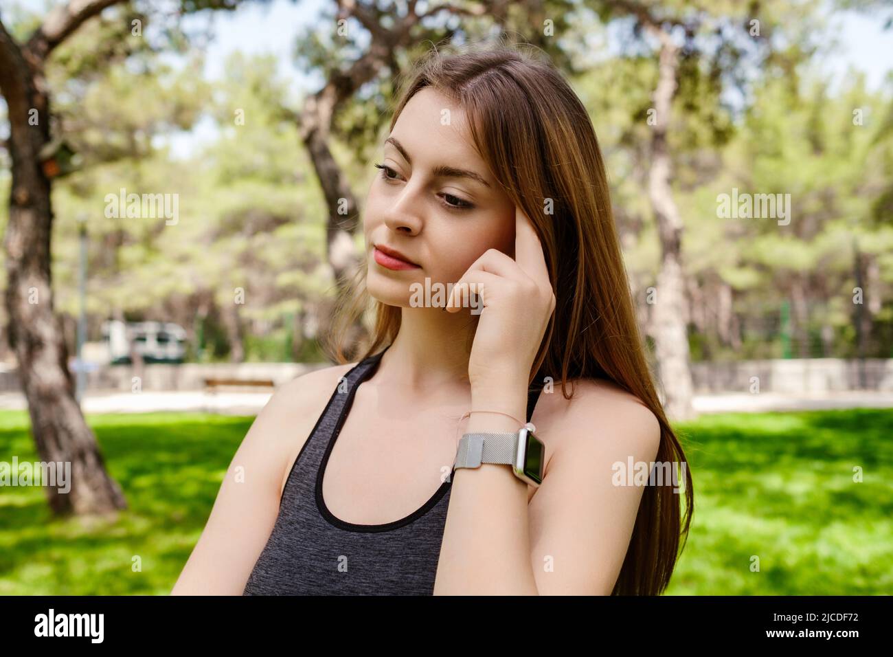 Giovane bella donna che indossa abiti sportivi sul parco cittadino, all'aperto le dita toccano la testa in profondità nei pensieri, pensando a cose importanti. Speranza. Sadne Foto Stock