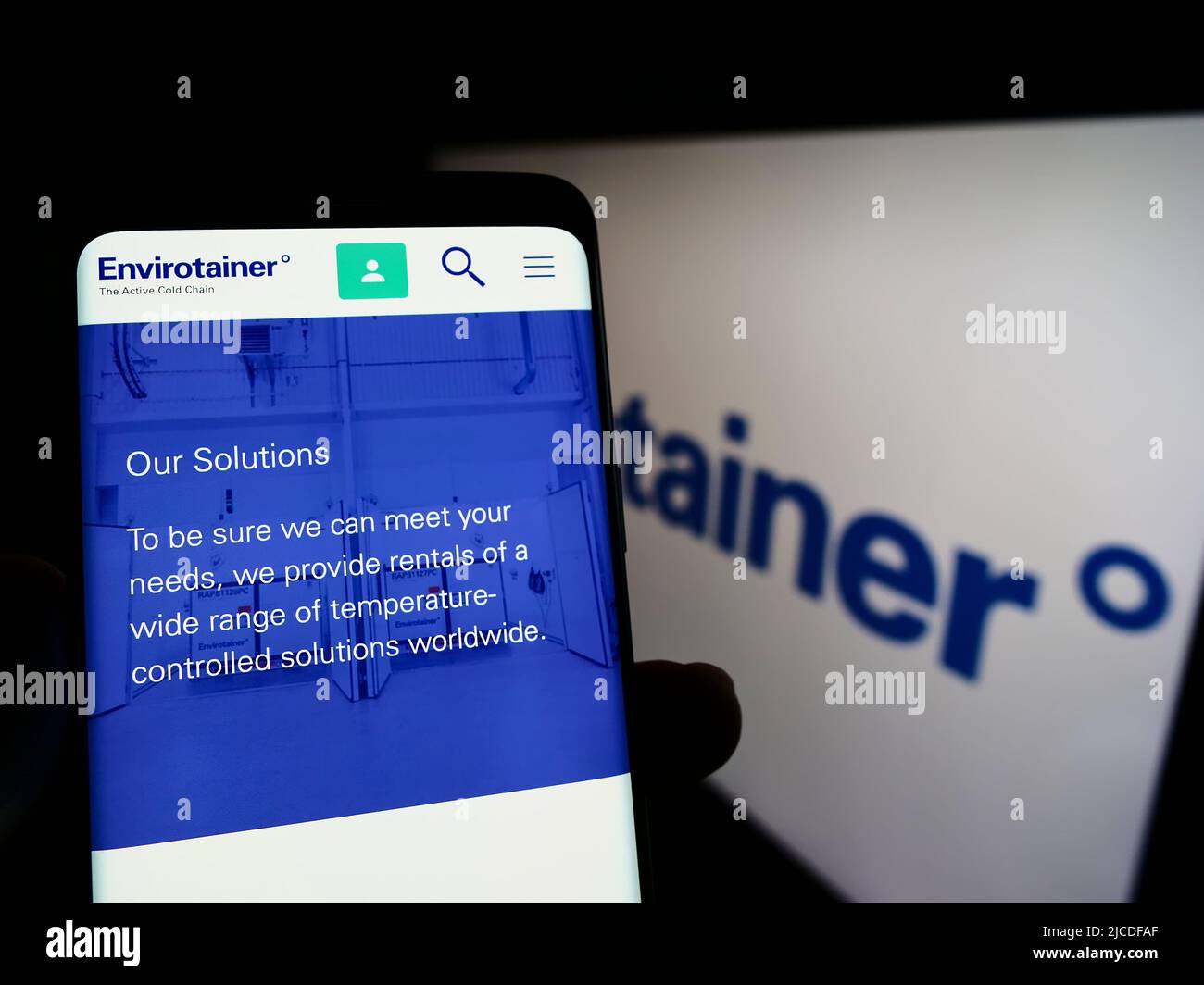 Persona che tiene il cellulare con il sito web della società di logistica svedese Envirotainer AB sullo schermo di fronte al logo. Concentrarsi sul centro del display del telefono. Foto Stock