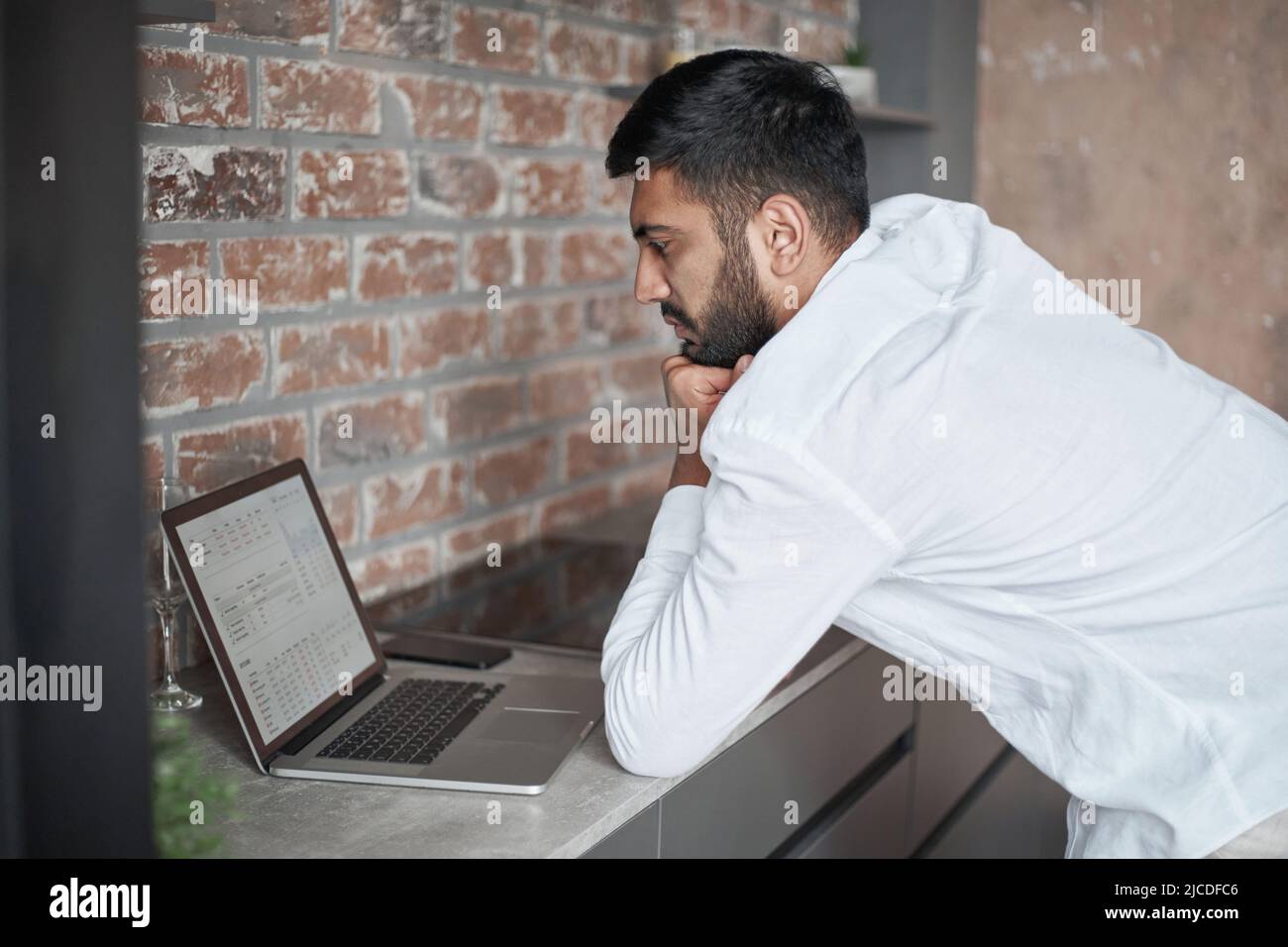giovane uomo che usa un computer portatile in cucina. Foto Stock