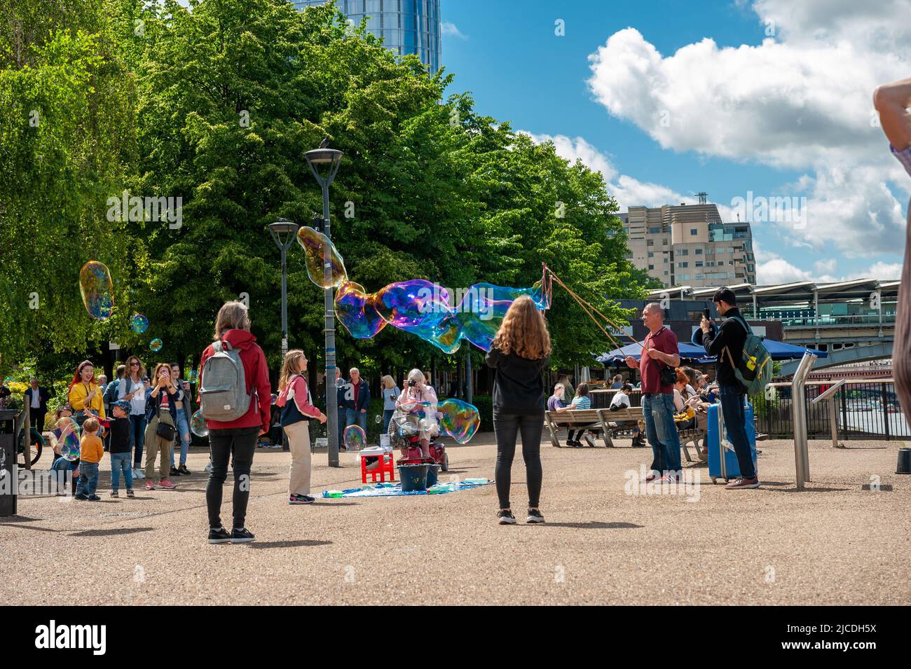 Londra, Inghilterra, Gran Bretagna - 6 giugno 2022: Un gruppo di bambini che giocano con palloncini di sapone che galleggiano in aria sulle rive del Tamigi Foto Stock