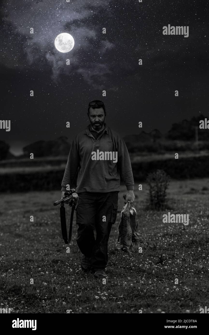 uomo che spara ai conigli di notte Foto Stock