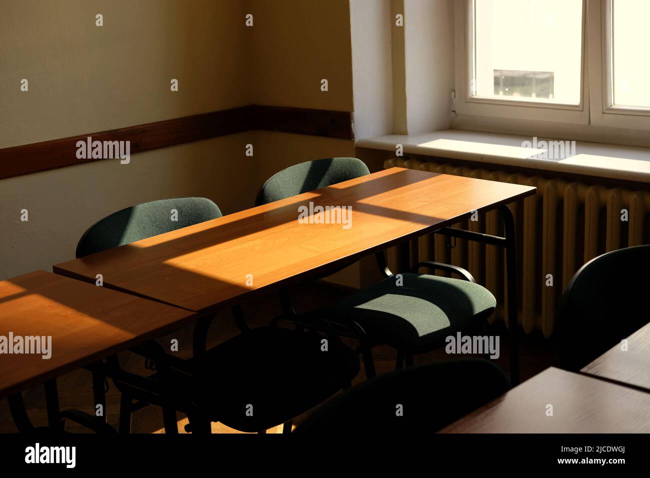 sole mattutino su scrivanie e sedie in aula vuota - in attesa che gli studenti entrino Foto Stock